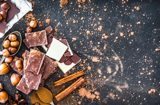 Chocolate in plates and spices in the spoons on black table