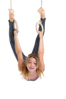Teenage girl exercising on gymnastic rings. Smiling teenager wearing sports clothes doing sports against white background. Active healthy lifestyle concept