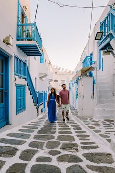 Mykonos Greece, Young man and woman in dress at the Streets of old town Mikonos during a vacation in Greece, Little Venice Mykonos Greece. couple mid age vacation Greece