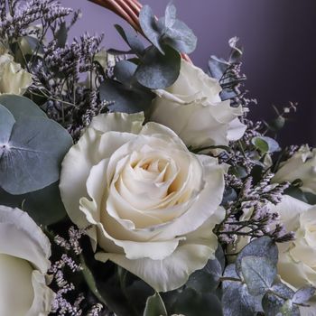 Bouquet of beautiful white roses in a wicker basket on a dark background. Perfect for greeting card