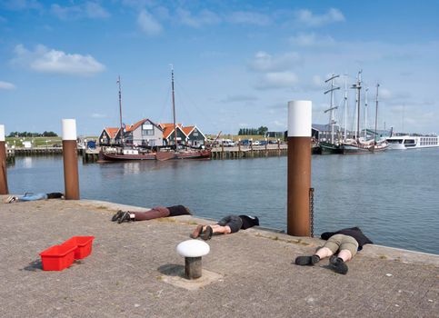 oudeschild, netherlands, 19 july 2021: old wooden sailing vessels in port of oudescild on dutch island of texel while boys fish for crabunder blue sky in the netherlands