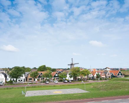dutch village with windmill of oudeschild on dutch island of texel seen from ijsselmeer dike in summer