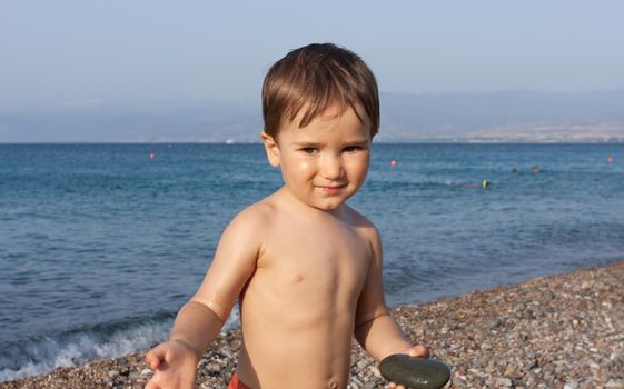 Healthy lifestyle. Little boy resting and having fun on a rocky beach on the Mediterranean coast