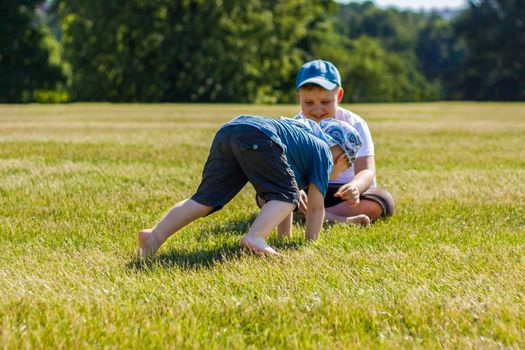 Cheerful children, two brothers, smile with joy. we are happy to walk and play on the lawn in warm sunny weather in the park. the emotions of children on the face. Happiness 