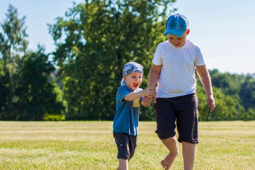 Cheerful children, two brothers, smile with joy. we are happy to walk and play on the lawn in warm sunny weather in the park. the emotions of children on the face. Happiness 