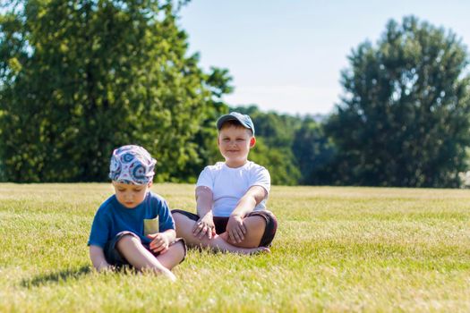 Cheerful children, two brothers, smile with joy. we are happy to walk and play on the lawn in warm sunny weather in the park. the emotions of children on the face. Happiness 