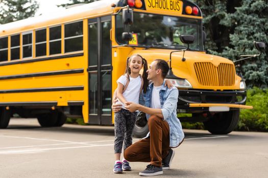 Girl with father going back to school near the school bus