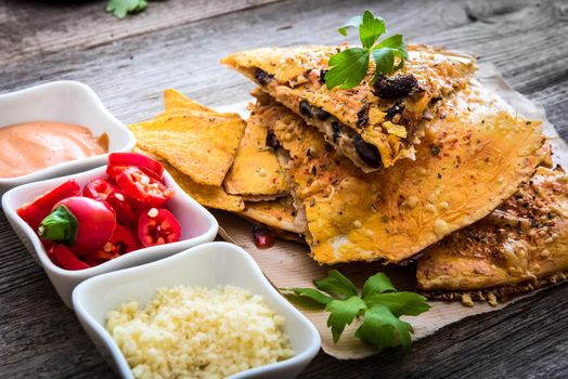quesadilla on parchment with sause and spices on a wooden background