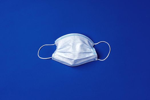 Medical face mask on blue background. Coronavirus covid-19 prevention concept