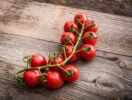 branch of cherry tomatoes on a wooden background
