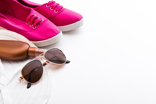 Beach accessories. Summer shoes and hat with sunglasses and suntan lotion on a white background
