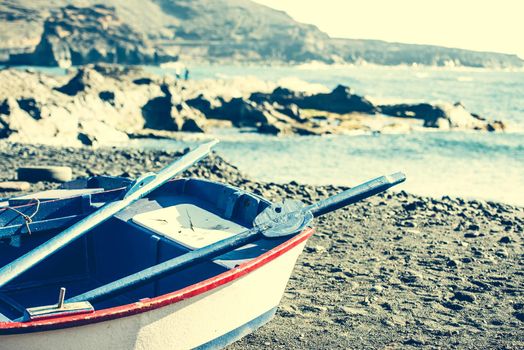 boat on a sandy shore on rocky coastline background