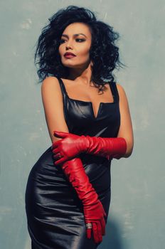 Luxurious Asian woman posing in black leather dress and red gloves. Dominant Fetish Lady. - image