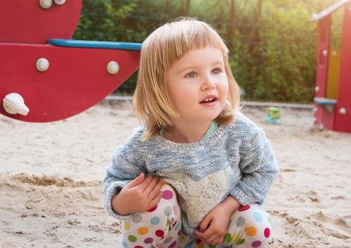 cute little girl in a sandbox on a playground