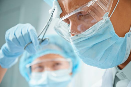 Nurse assistant rubs forehead of man surgeon on operation