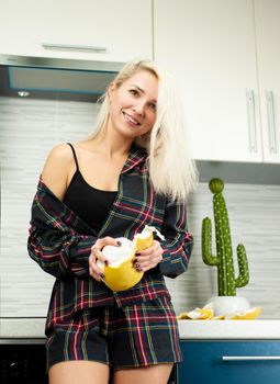 the Woman in the kitchen in home clothes cleaning fruit pomelo with emotions