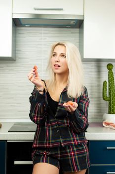 the woman in the kitchen in home clothes with a peeled pomelo fruit eats and laughs