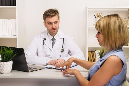 Young woman on a consultation with a male surgeon or therapist in his office. Selective focus on the doctor.