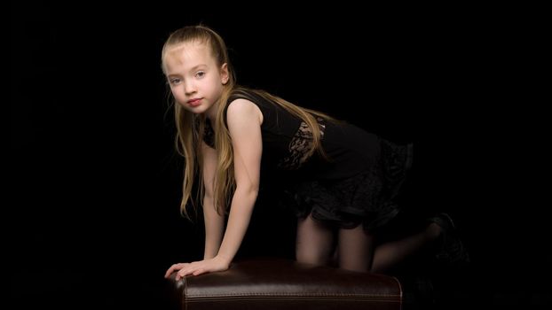 Beautiful little girl in a dance suit posing in the studio. Creative development concept of a child. On a black background.