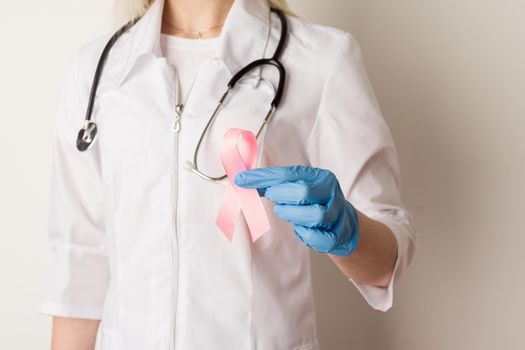 Woman doctor holding a pink ribbon in her hands - image