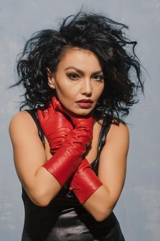 Luxurious Asian woman in black leather dress and red gloves holding herself by the throat. Dominant Fetish Lady. - image