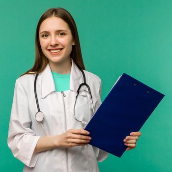 Happy smiling young female doctor with clipboard, isolated over background - image