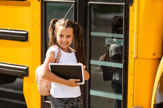 Girl with backpack near yellow school bus. Transport for students