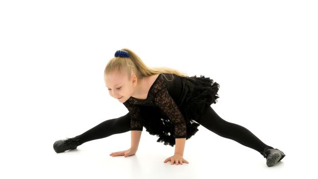 A little girl performs a gymnastic twine. The concept of fitness and sports. Isolated on white background.