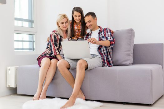 Happy family using laptop together on sofa in house