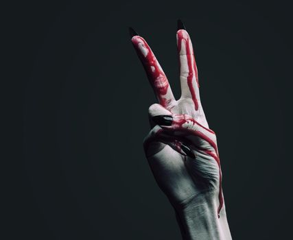 Vampire hand in blood on dark background, peace hand sign. Halloween or horror theme