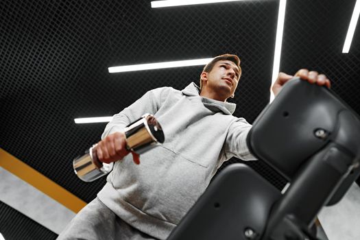 Determined handsome young male working out in gym with dumbbells, close up