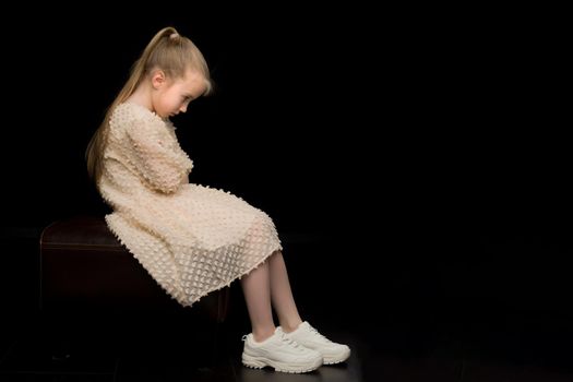 Beautiful studio portrait of a little girl in profile. On a black background.