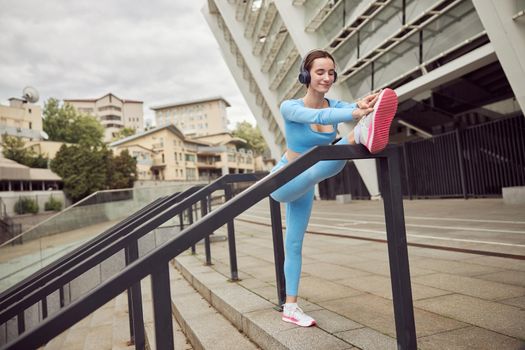 Beautiful fit caucasian woman is doing exercises outdoors at the city