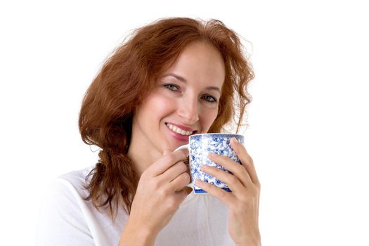 Smiling woman holding porcelain mug. Cheerful brown haired woman posing with cup of coffee or tea in her hands against white background. Female person enjoying of hot drink in the morning