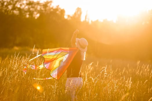 Portrait of a young and carefree woman launching kite on the greenfield. Concept of active lifestyle in nature