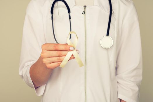 Yellow ribbon symbolic color for Sarcoma Bone cancer, Bladder health, Liver disease, Spina Bifida Awareness Month and suicide prevention in doctor's hand - Image