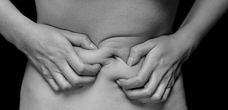 Unrecognizable woman holds her abdomen, menstrual pain, monochrome image