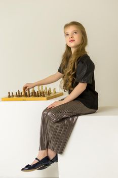 A little girl is playing chess. The concept of creative education of a child, training of thinking.
