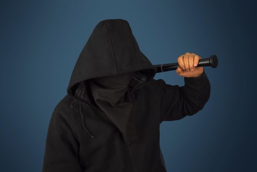Hooligan man in hood and mask holds baseball bat