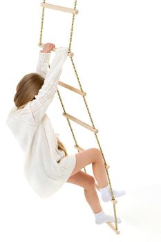 The girl climbs the rope ladder. Cheerful child on a white background. Active healthy lifestyle concept