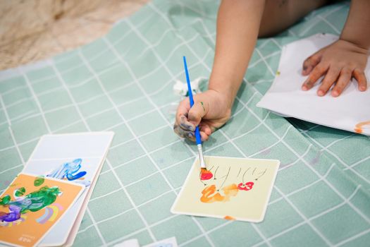 Focus on hands on paper. Children use paintbrushes to paint watercolors on paper to create their imagination and enhance their learning skills