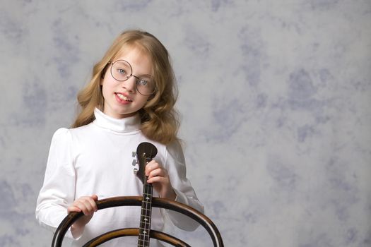 Cute little girl learning to play the plucked musical instrument, domra.