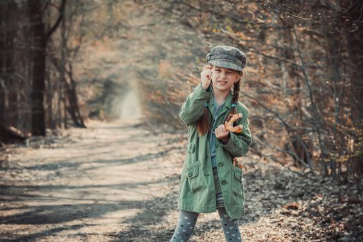 little girl playing with a slingshot in the woods, photo in vintage style