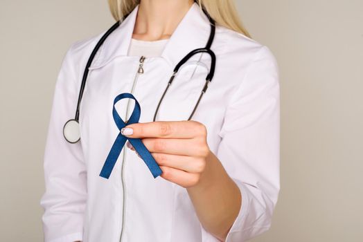 Doctor hands holding blue ribbon, diabetes and Colorectal Cancer Awareness - Image