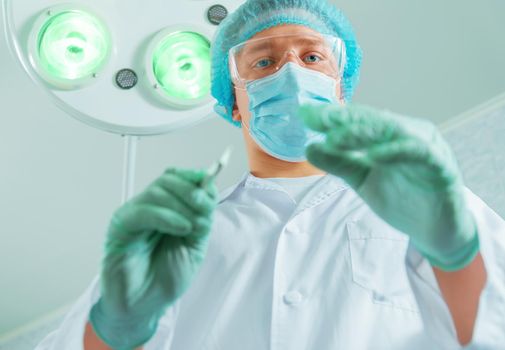 Doctor surgeon holds a scalpel in an operating room, focus on scalpel