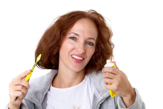 Woman holding toothbrush and toothpaste. Close up shot of cheerful woman wearing casual clothes with tools for teeth cleaning posing against white background. Healthy lifestyle, daily routine