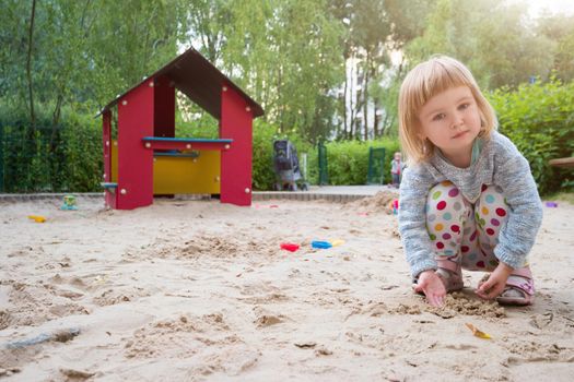 cute little girl in a sandbox on a playground