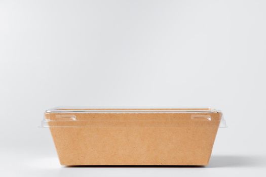 Craft paper disposable box with plastic cover on grey background, copy space, close up