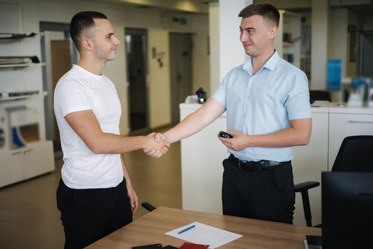 Men shakes hands after successful sale in car showroom.