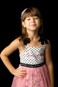 Portrait of cheerful girl in stylish summer clothes. Front view of beautiful girl wearing sundress and headband posing with hand on her waist against black background and smiling at camera